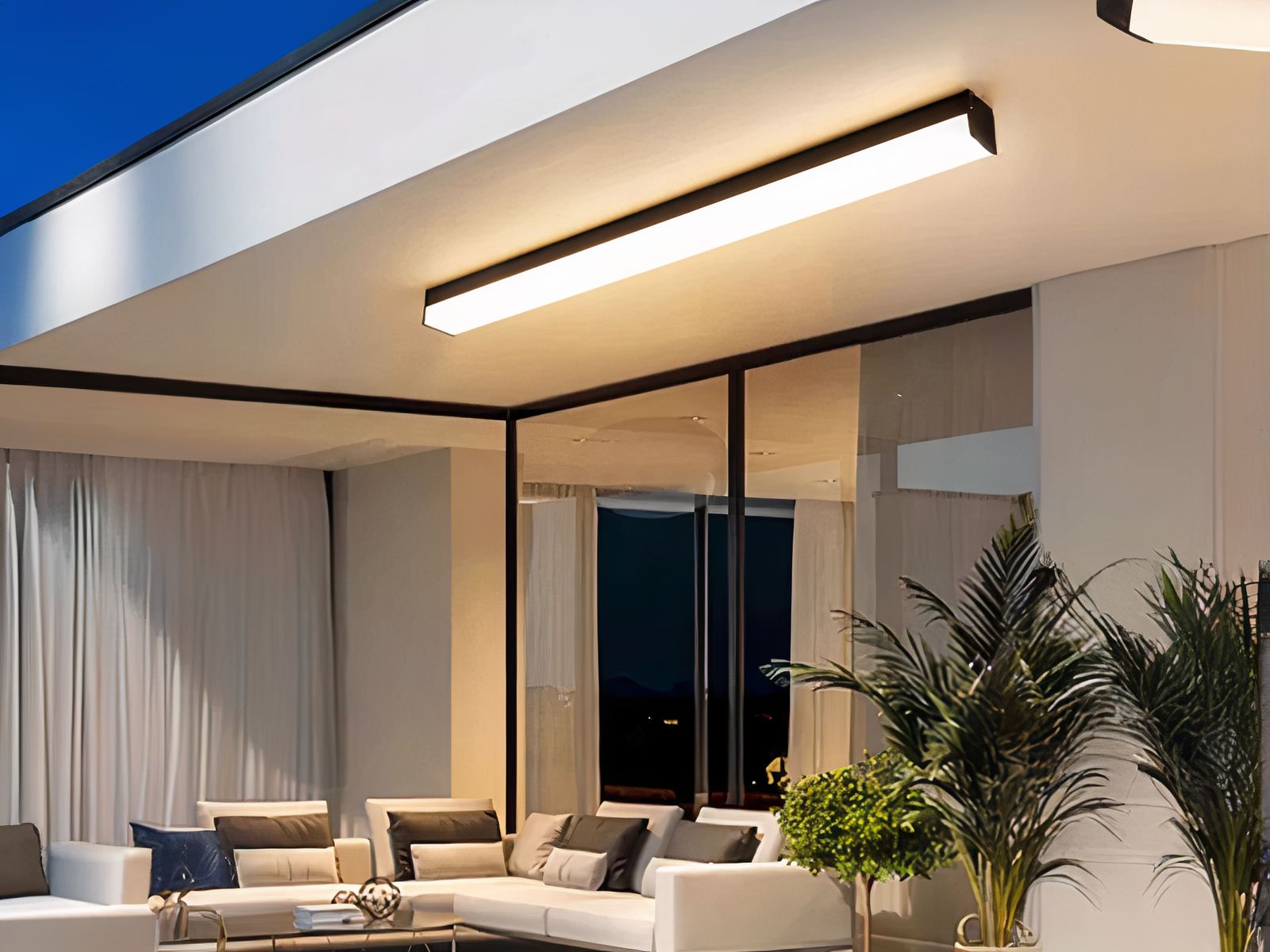 Plafonnier LED exterieur lumineux et durable installé au-dessus d'un canapé avec des vitres à côté et des plantes vertes
