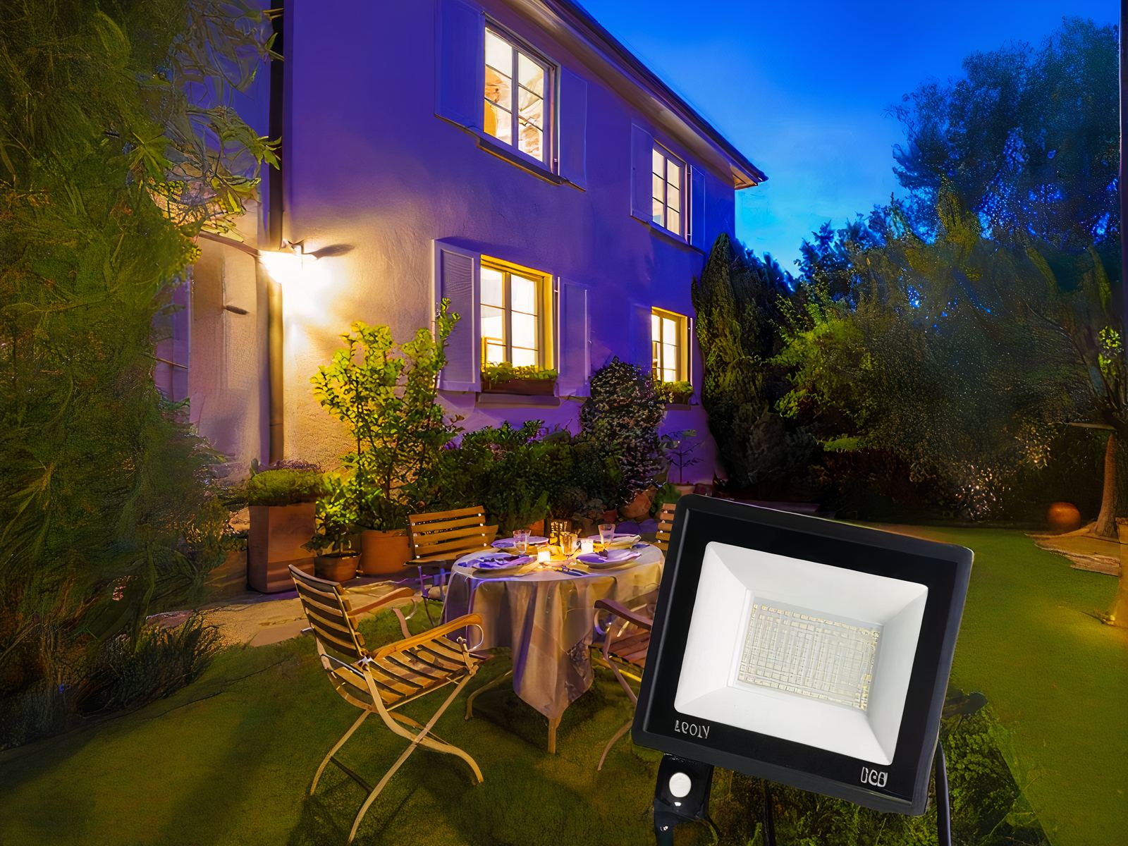 Projecteur extérieur LED avec détecteur de mouvement installé sur la façade d'une maison avec une table et des chaises dans un jardin