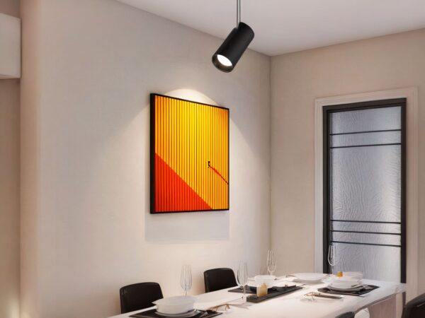 Projecteur LED design et rotatif installé sur un plafond avec un tableau contre le mur et une table en dessous