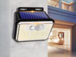 Projecteur LED solaire tendance et sans fil installé sur un mur gris avec une maison en fond