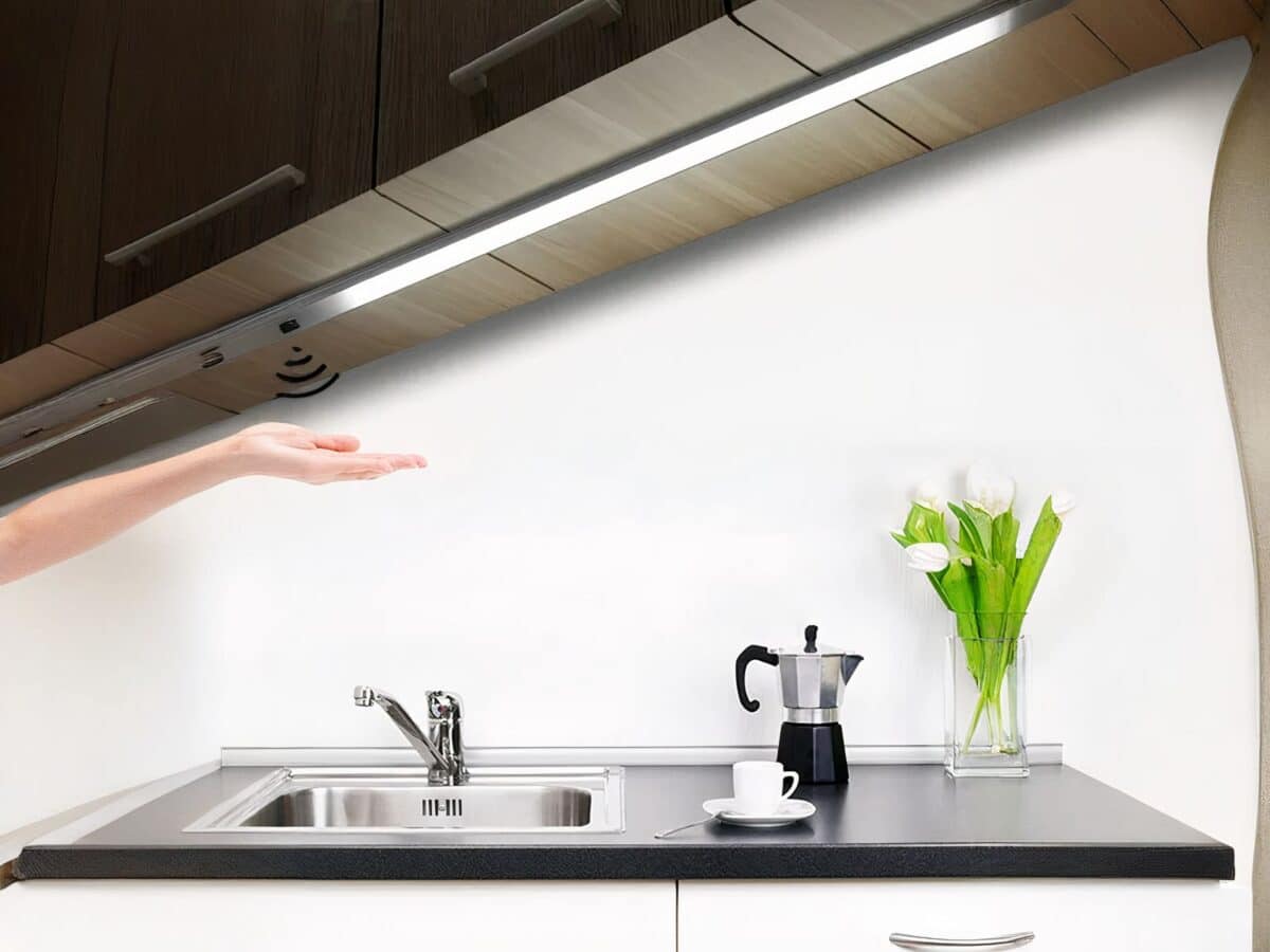 Réglette LED cuisine avec capteur de balayage Réglette LED de cuisine avec capteur de balayage, allumée et installée sous un meuble haut au-dessus d'un évier.