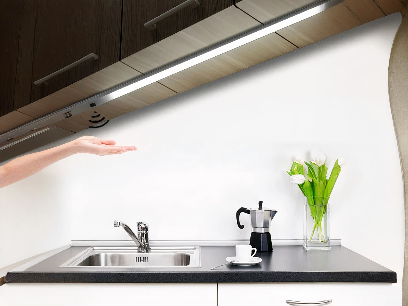 Réglette LED cuisine avec capteur de mouvements Réglette LED de cuisine avec capteur de balayage, allumée et installée sous un meuble haut au-dessus d'un évier.