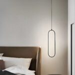 Suspension LED minimaliste moderne ovale noire Suspension LED minimaliste ovale noire allumée, à côté d'un lit comme une lampe de chevet.