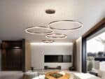 Suspension LED composée de 4 anneaux de différente taille, dispersés au plafond dans un salon moderne.