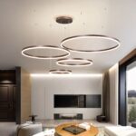 Suspension LED moderne avec anneaux brossés Suspension LED composée de 4 anneaux de différente taille, dispersés au plafond dans un salon moderne.
