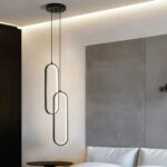 Suspension LED double moderne ovale noire Suspension LED double ovale noire, installée à côté d'un lit comme une lampe de chevet.
