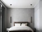 Chambre avec un grand lit et une tête de lit capitonnée marron, et une suspension LED tube noire de chaque côté du lit en guise de lampe de chevet.