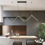 Suspension LED vague au design moderne Suspension LED noire, en forme de vague, installée au-dessus d'un mange-debout dans une cuisine très moderne.