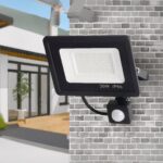 Projecteur extérieur LED détecteur de mouvement 180° Projecteur LED extérieur à détecteur de mouvement installé sur un mur en briques grises.