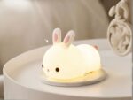 Lampe LED rechargeable style veilleuse lapin sur une table avec un réveil à côté