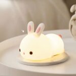 Lampe LED rechargeable style veilleuse lapin sur une table avec un réveil à côté