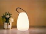 Lampe LED rechargeable télécommandée style lanterne posée sur une table avec un bouquet de fleurs