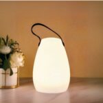 Lampe LED rechargeable télécommandée style lanterne Lampe LED rechargeable télécommandée style lanterne posée sur une table avec un bouquet de fleurs