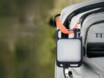 Lampe de travail LED mini porte-clés, accrochée à un sac à dos gris.