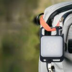Lampe de travail LED mini porte-clés multifonction Lampe de travail LED mini porte-clés, accrochée à un sac à dos gris.