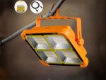 Lampe de travail LED solaire rechargeable, orange, accrochée à une branche d'arbre.
