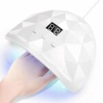 Lampe LED ongle de voyage spéciale gel UV Lampe LED ongle de voyage, spéciale gel UV, allumée avec la main d'une personne. Sur fond blanc.