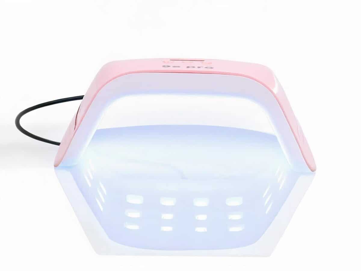 Lampe LED ongle rose compacte et puissante Lampe LED ongle rose et blanche, compacte et puissante, allumée sur fond blanc.