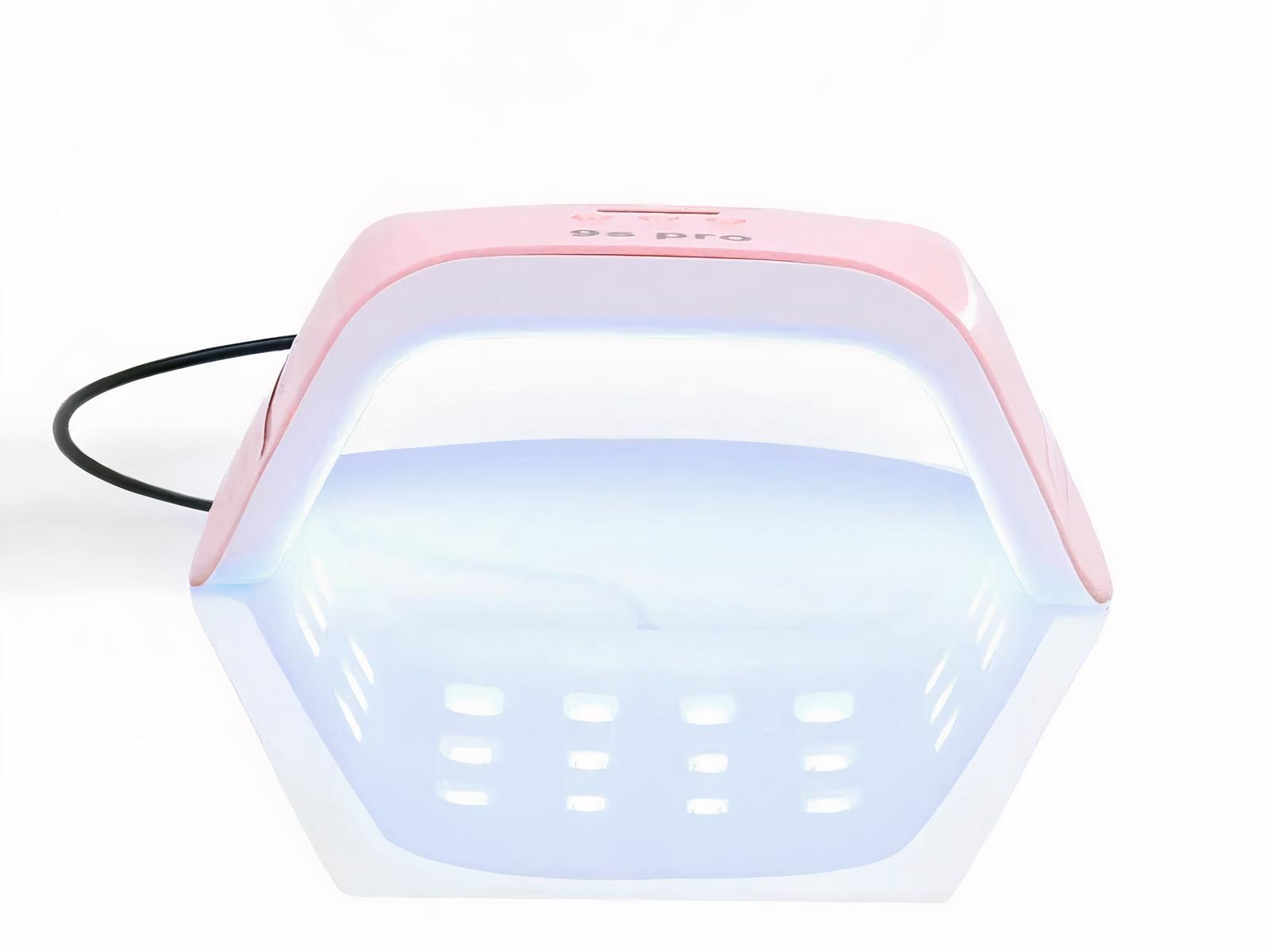 Lampe LED ongle rose et blanche, compacte et puissante, allumée sur fond blanc.