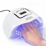 Lampe LED ongle UV à capteur infrarouge Lampe LED ongle UV à capteur infrarouge, allumée avec la main d'une femme à l'intérieur.