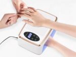 Lampe LED ongle UV grand format, blanche et dorée, Utilisée par deux personnes, on ne voit que leurs mains. Une fait la manucure à l'autre.