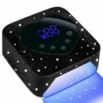 Lampe LED ongle UV portable noire à strass et écran tactile Lampe LED ongle UV portable noire à strass et écran en forme de cœur, allumée, sur fond blanc.