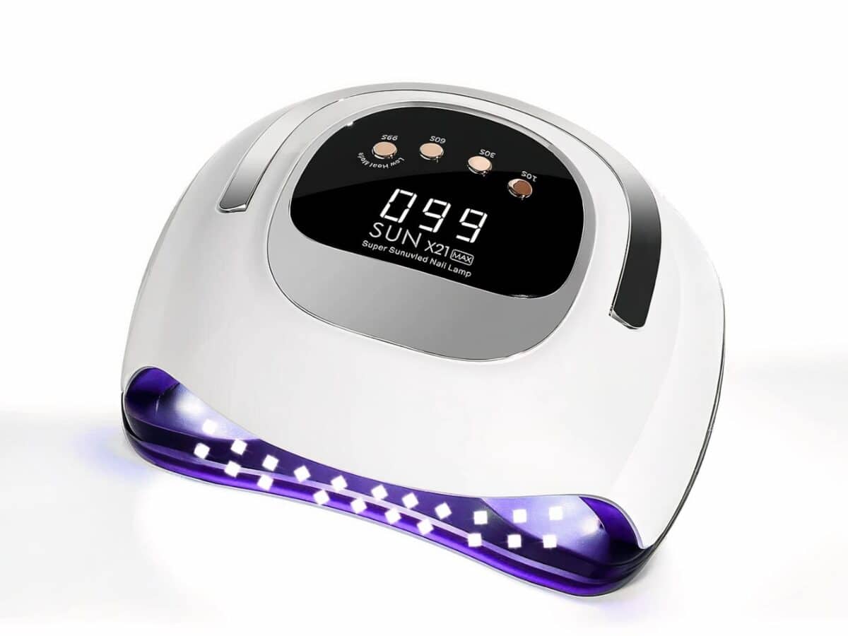 Lampe LED ongle UV pour vernis gel, allumée, blanche avec un écran noir et des boutons beiges, sur un fond blanc.