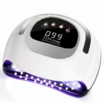 Lampe LED ongle UV pour vernis gel Lampe LED ongle UV pour vernis gel, allumée, blanche avec un écran noir et des boutons beiges, sur un fond blanc.