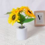 Lampe LED rechargeable effet pot de fleurs Lampe LED rechargeable effet pot de fleurs posée sur une table avec une nappe blanche et un cadre en fond