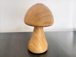 Lampe LED rechargeable en forme de champignon posée sur une table avec un mur gris en fond