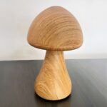 Lampe LED rechargeable en forme de champignon posée sur une table avec un mur gris en fond