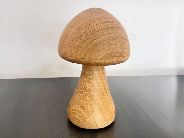 Lampe LED rechargeable en forme de champignon posée sur une table avec un mur gris en fond