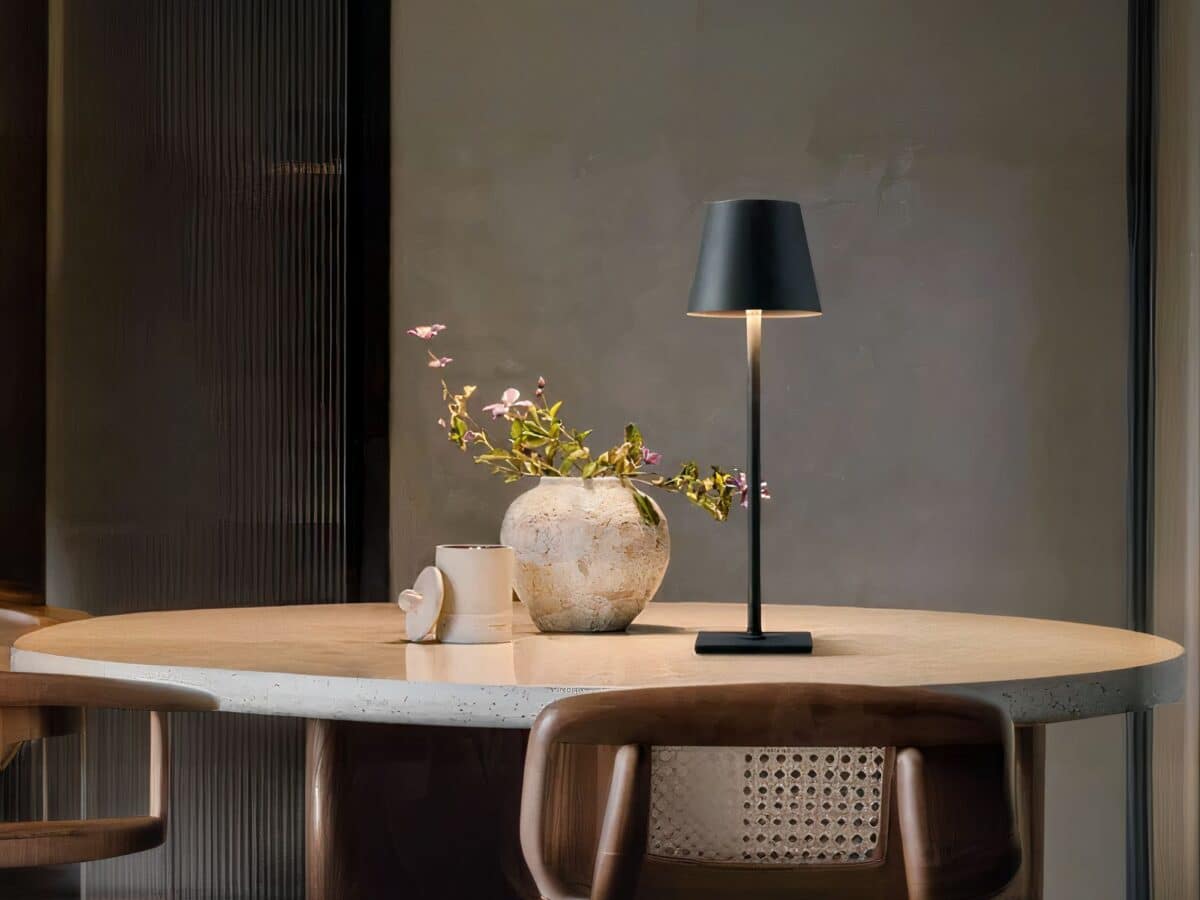 Lampe LED rechargeable style lampe de table moderne Lampe LED rechargeable style lampe de table moderne posée sur une table avec un pot de fleur et un récipient à côté