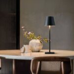 Lampe LED rechargeable style lampe de table moderne posée sur une table avec un pot de fleur et un récipient à côté