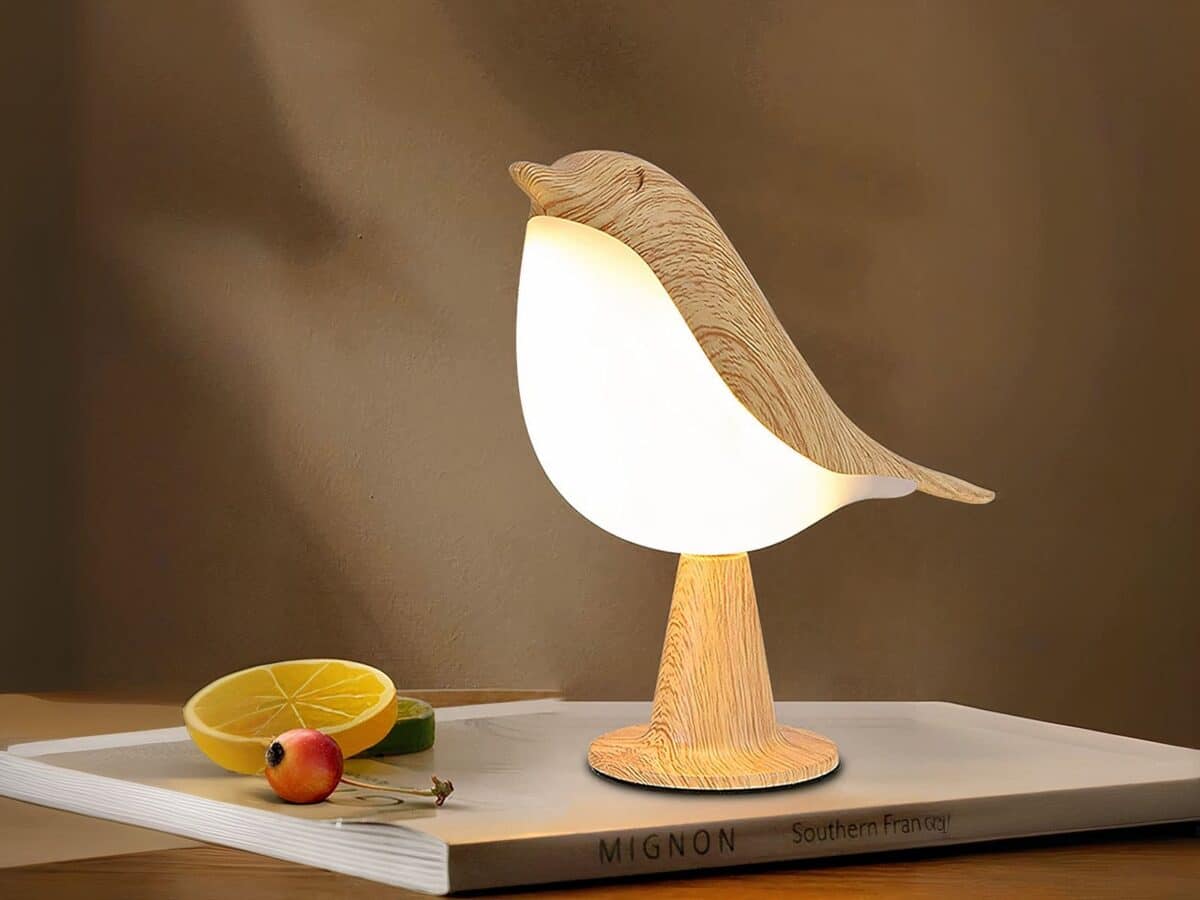 Lampe LED rechargeable style oiseau en bois Lampe LED rechargeable style oiseau en bois posée sur un livre avec une rondelle de citron