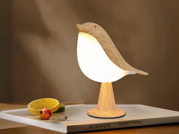 Lampe LED rechargeable style oiseau en bois posée sur un livre avec une rondelle de citron