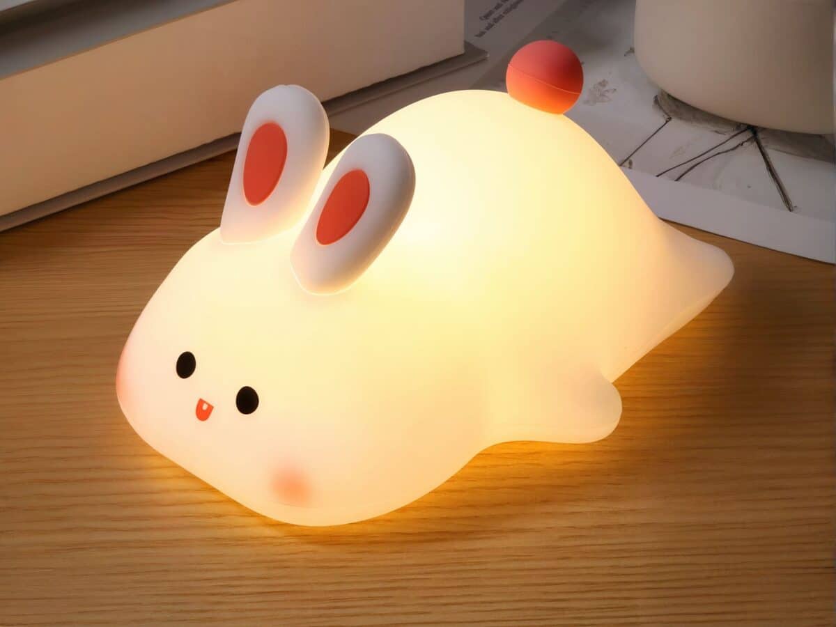 Lampe LED sans fil et rechargeable style lapin Lampe LED sans fil et rechargeable style lapin sur une table en bois marron avec un livre en fond