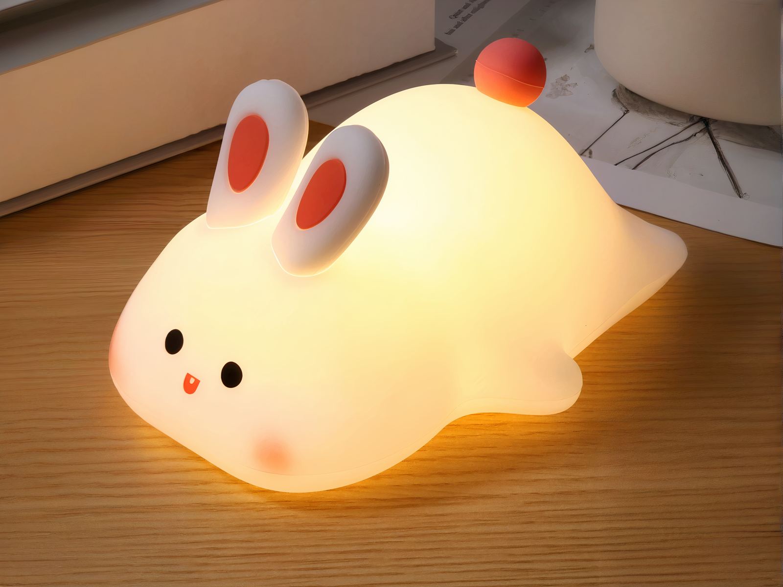 Lampe LED sans fil et rechargeable style lapin sur une table en bois marron avec un livre en fond