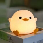 Lampe LED sans fil tactile en forme de canard Lampe LED sans fil tactile en forme de canard posée sur un livre