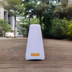 Lampe LED sans fil télécommandée et étanche Lampe LED sans fil télécommandée et étanche posée en extérieur avec des arbres et des buissons en fond