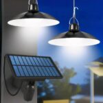 Lot deux lampes LED solaires suspendues avec télécommande Lot deux lampes LED solaire allumées, suspendues dans un jardin, il fait presque nuit.