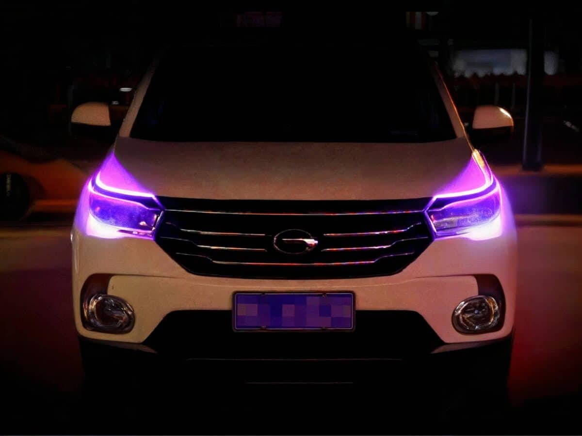 Lot deux rubans LED extérieurs flexible phares voiture Voiture blanche, dans un espace sombre, avec les deux rubans LED installés sur les phares et allumés en violet.
