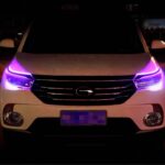 Lot de deux rubans LED extérieurs flexibles pour phares de voiture Voiture blanche, dans un espace sombre, avec les deux rubans LED installés sur les phares et allumés en violet.