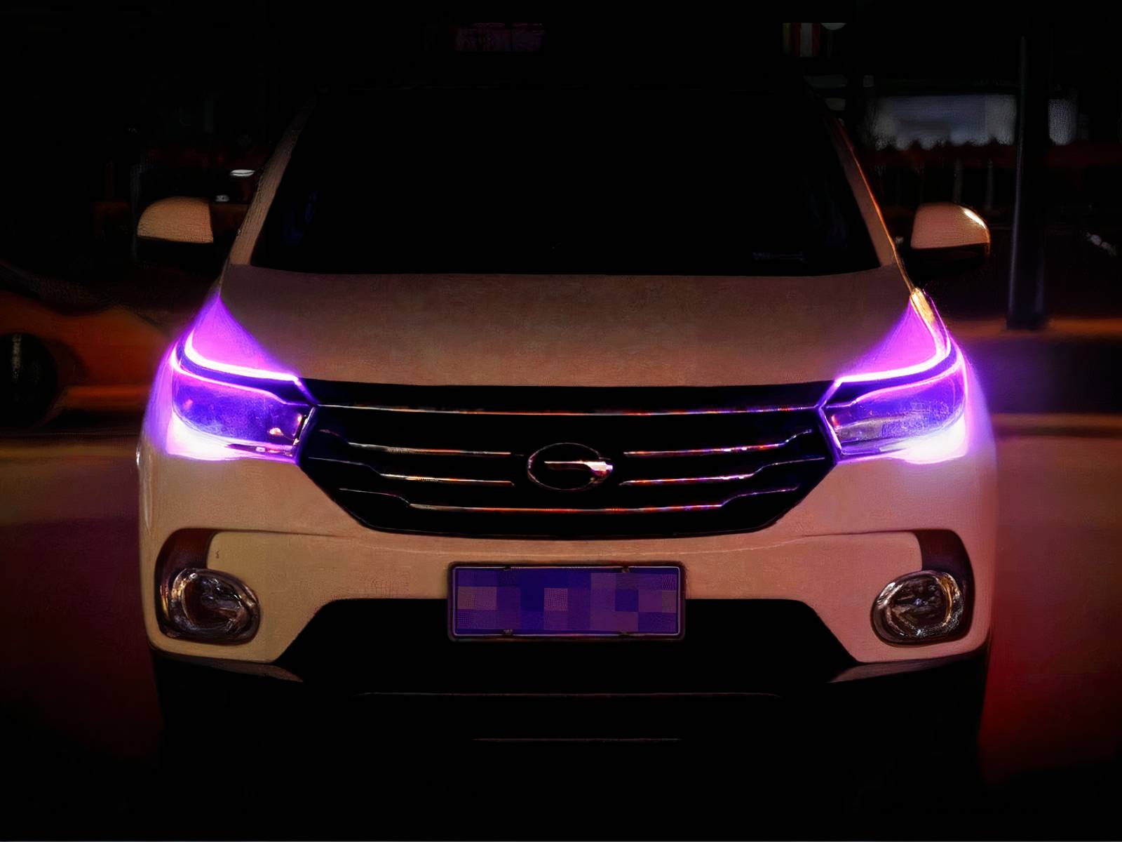 Voiture blanche, dans un espace sombre, avec les deux rubans LED installés sur les phares et allumés en violet.