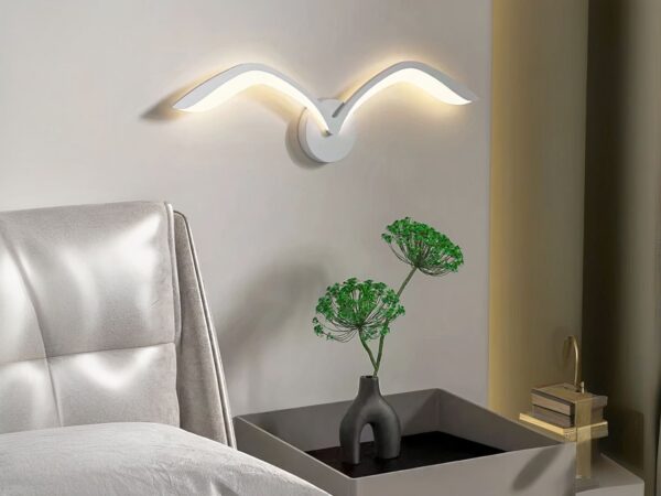 Luminaire LED mural créatif et original en forme d'oiseau allumé dans une chambre à côté d'un lit