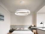Lustre LED cercle original blanc suspendu au-dessus d'un lit.