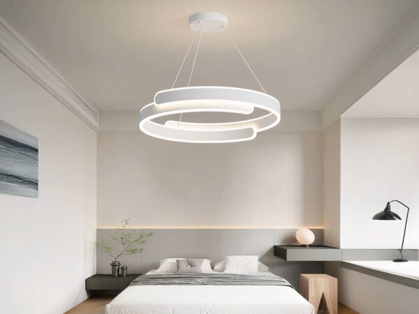 Lustre LED cercle original blanc suspendu au-dessus d'un lit.