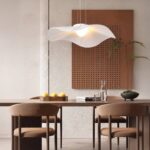 Lustre LED fleur en tissu blanc Lustre LED fleur blanche, allumé et installé au-dessus d'une table en bois, avec 4 chaises autour et un tableau sur le mur du fond.