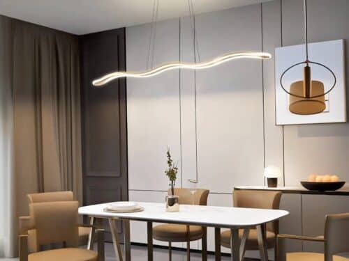 Lustre LED vague doré suspendue au-dessus d'une table blanche, avec des chaises autour.