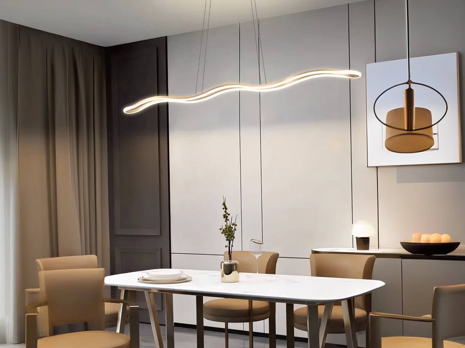 Lustre LED vague doré suspendue au-dessus d'une table blanche, avec des chaises autour.